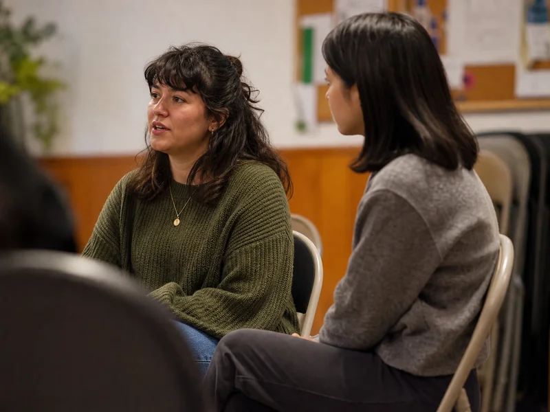 Two people in a workshop room having a quiet active listening conversation